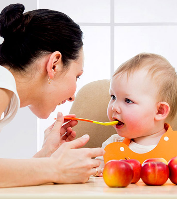 A mother feeds her baby some apple puree