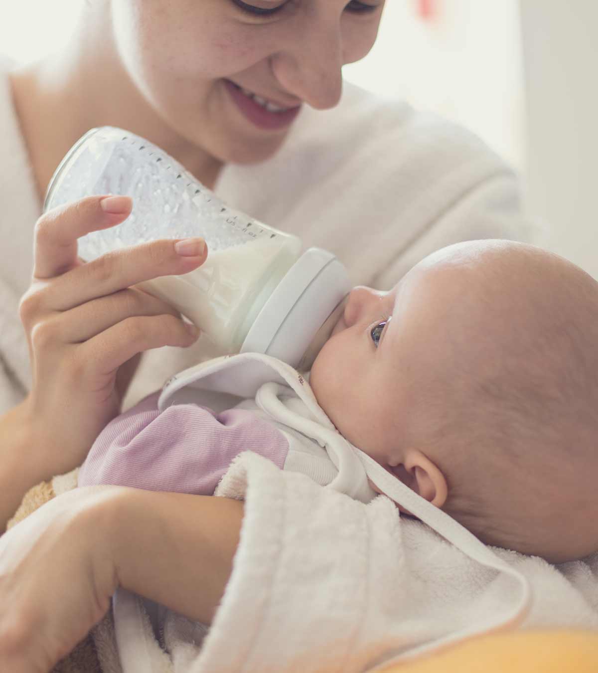 Mother Giving Formula To A Baby In Feeding Bottle