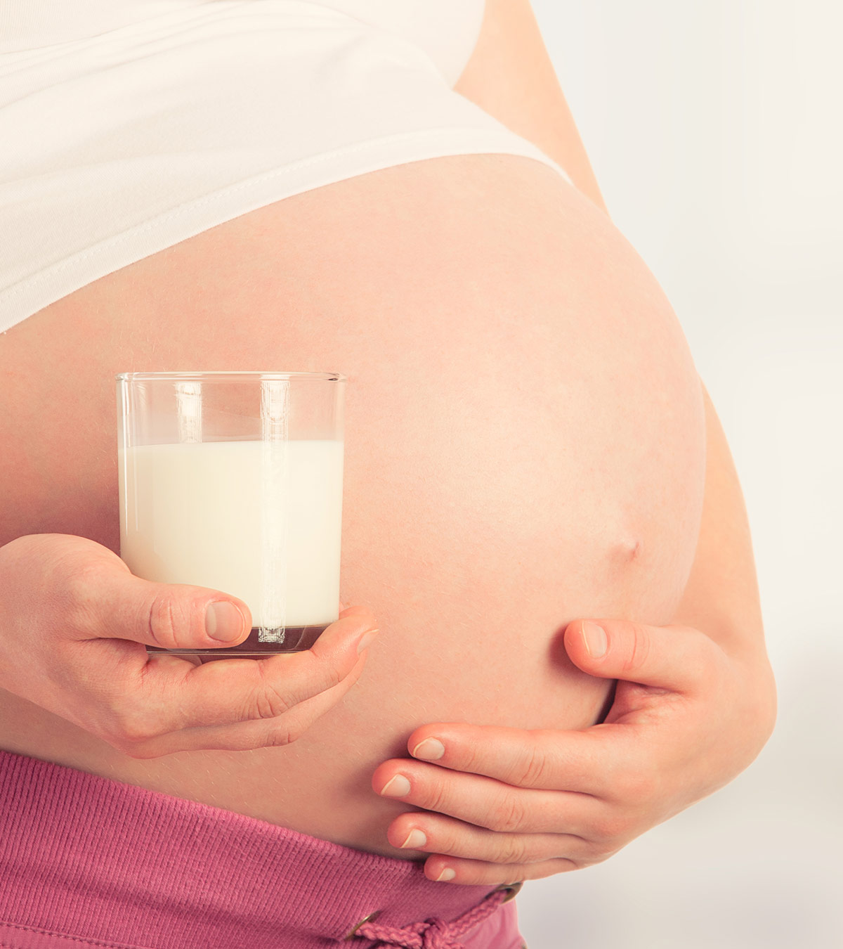 A pregnant lady holds a glass of soy milk